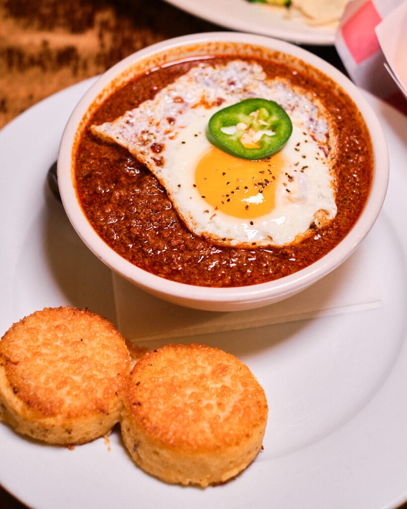 bowl of chili with egg and cornbread