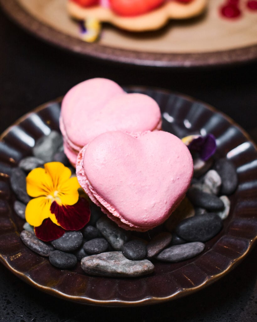 two heart shaped macarons on a plate.