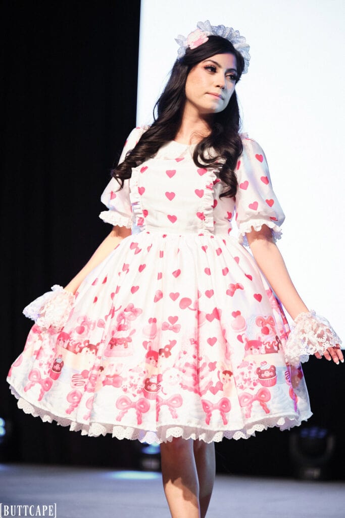 lolita model wearing white and pink dessert print dress looking away.