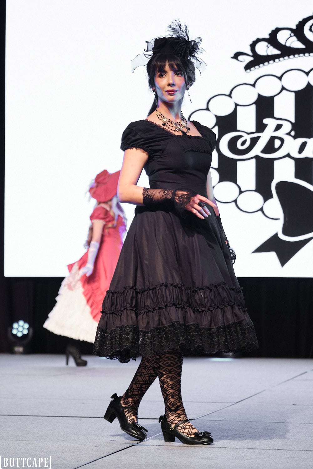 lolita model wearing all black classic dress posing looking at audience.