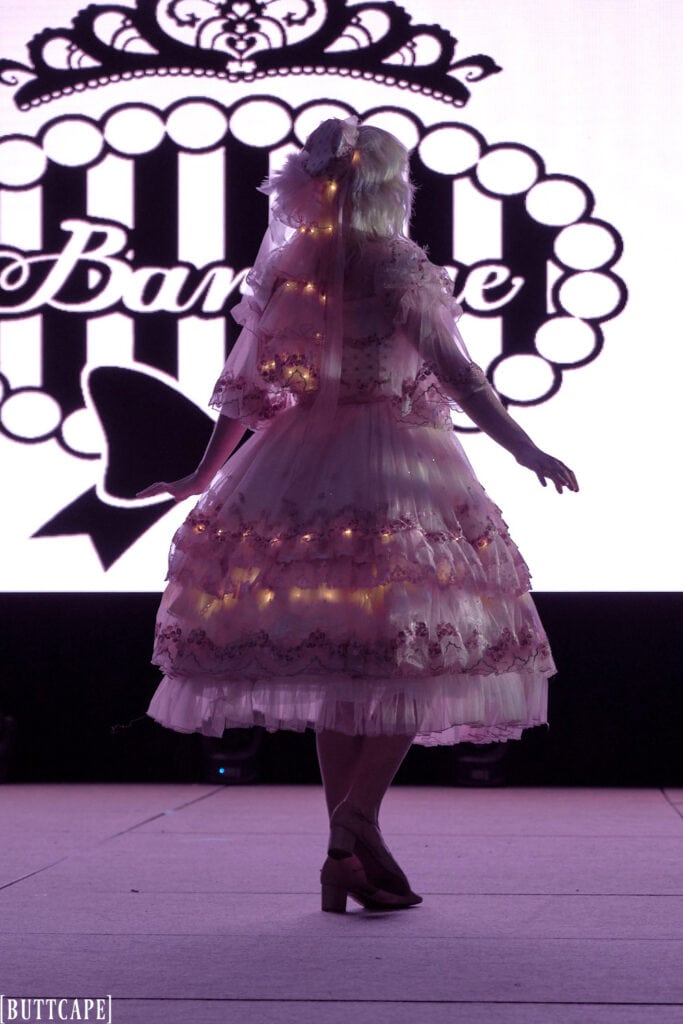 lolita model wearing lacy pink dress with LED lights in dark showing off backside of dress 2.