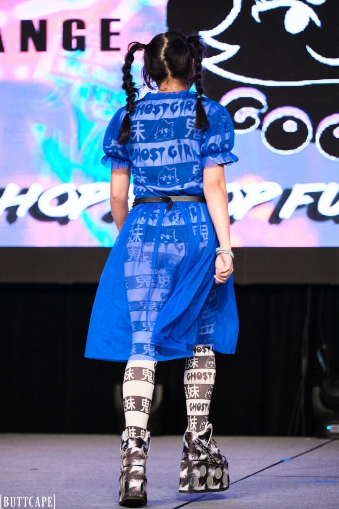 model wearing blue mesh dress walking down runway backside.