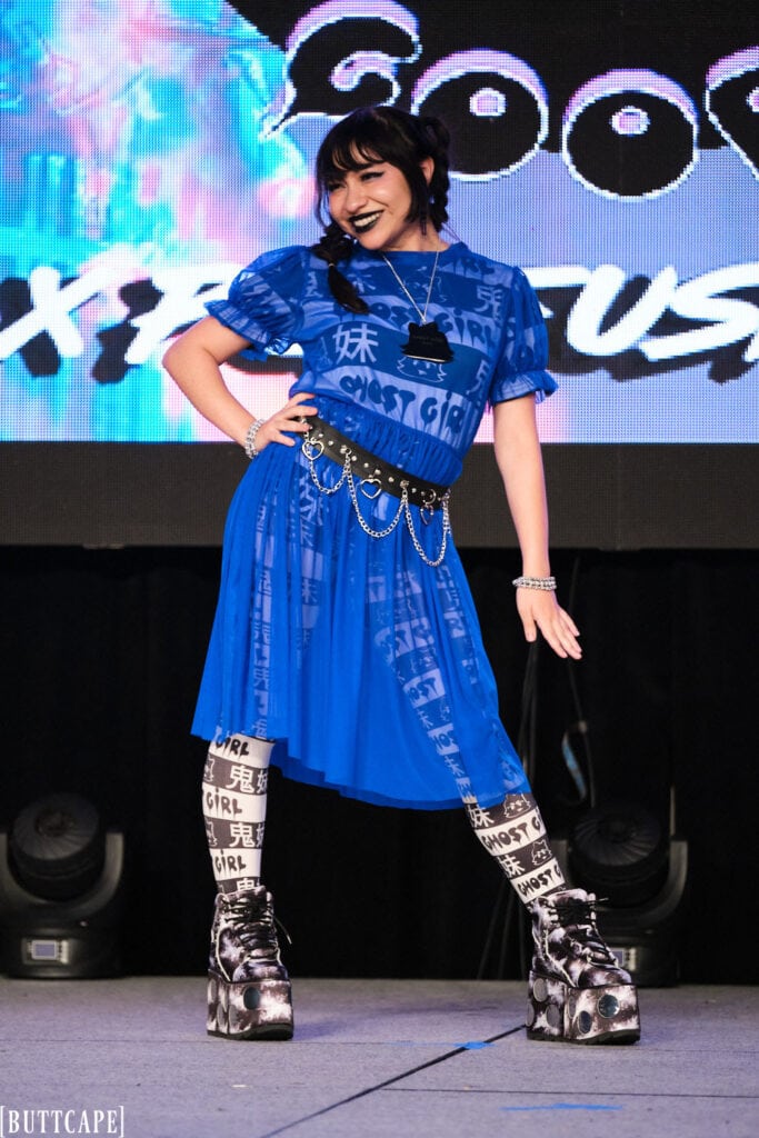 model wearing blue mesh dress smiling and posing.