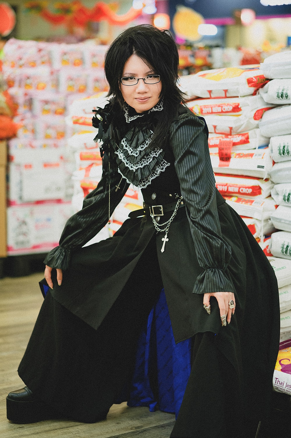 goth sitting on a bags of rice inside Asian grocery store.