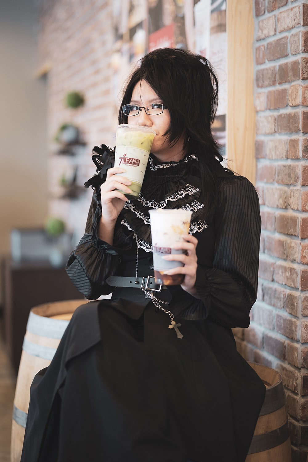goth holding 2 cups of 7leaves milk tea.
