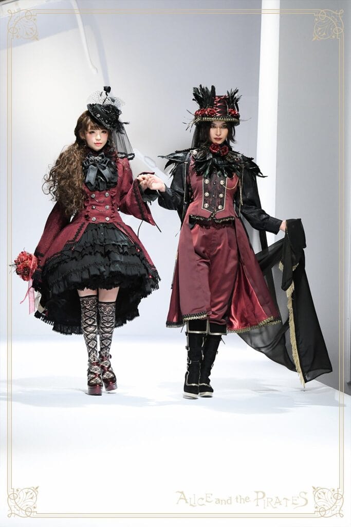 Two models Midori Fukasawa and Akira walking down runway in matching red and black lolita and ouji sets.