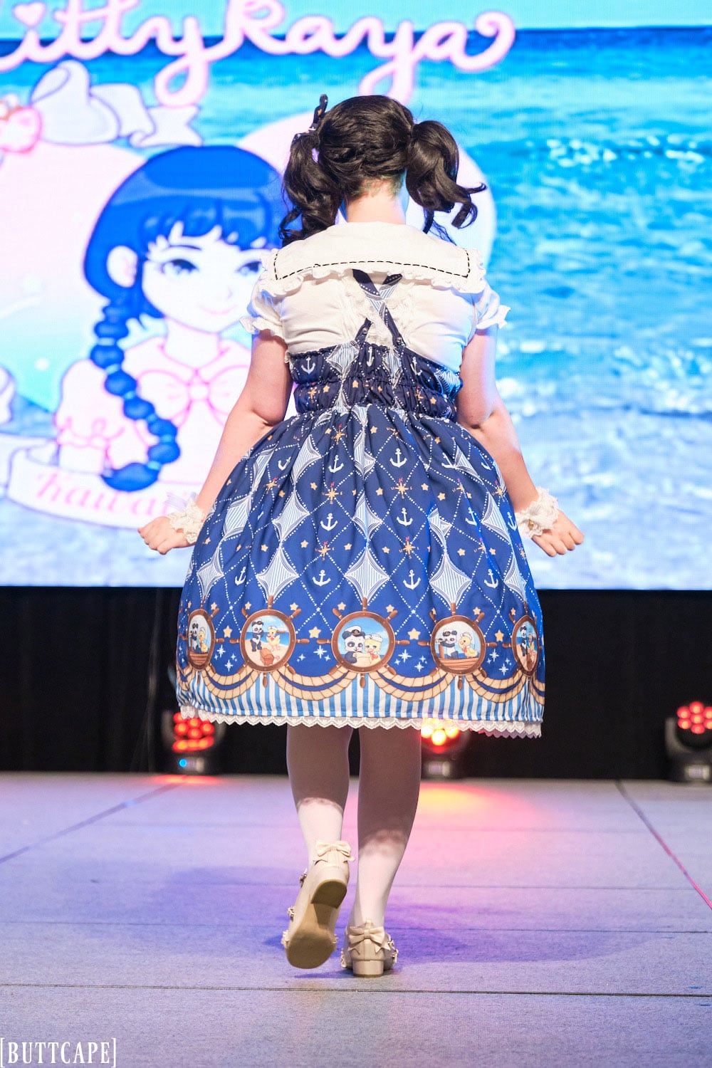 Kittykaya model 3 wearing blue sailor themed lolita dress with nautical animal theme - full body backside.