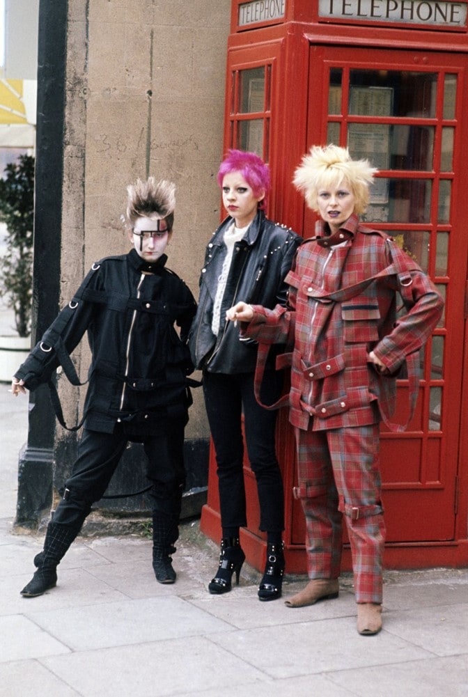 Three punk women in front of phone booth.