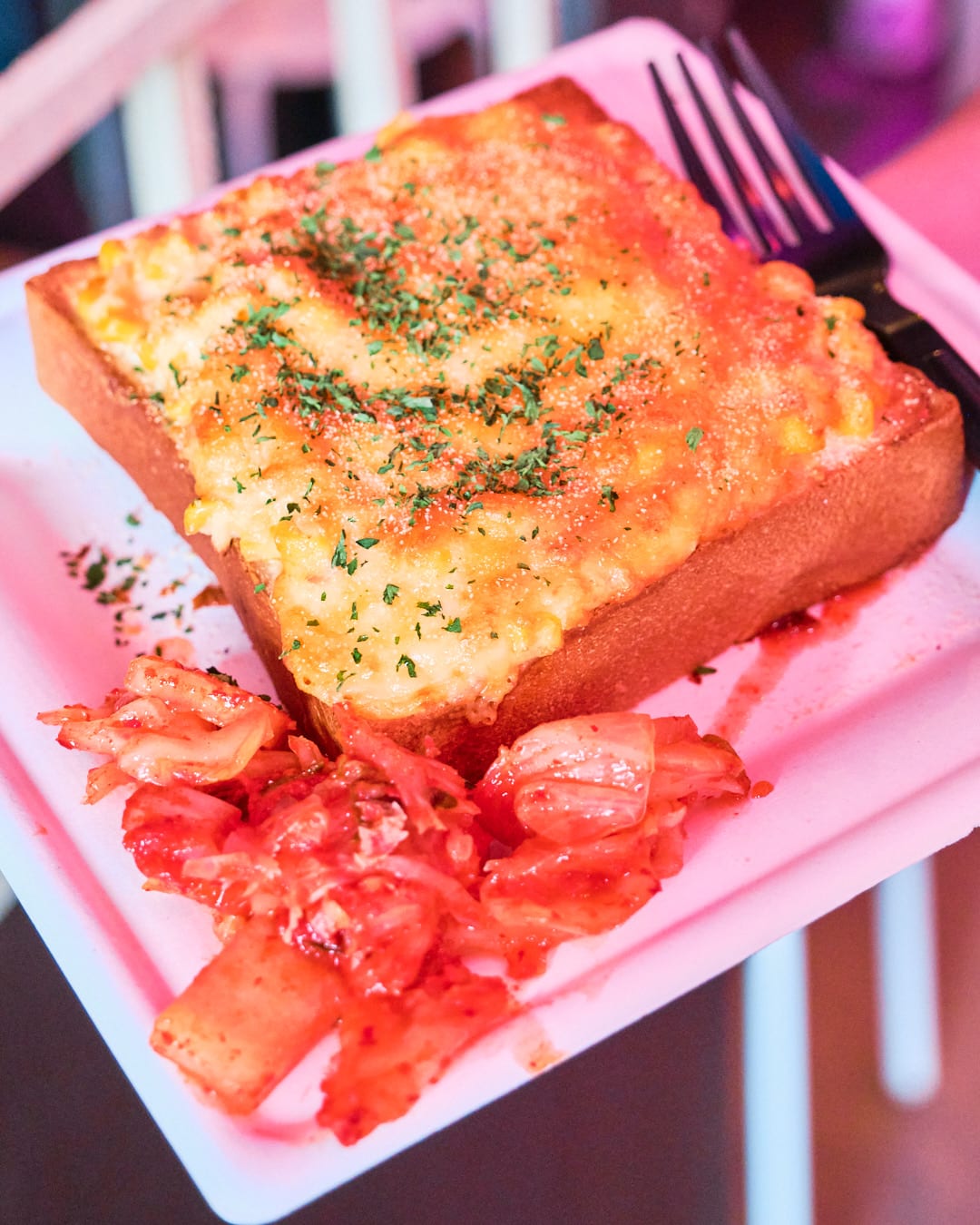 Slice of toast covered in egg and corn with side of kimchi.
