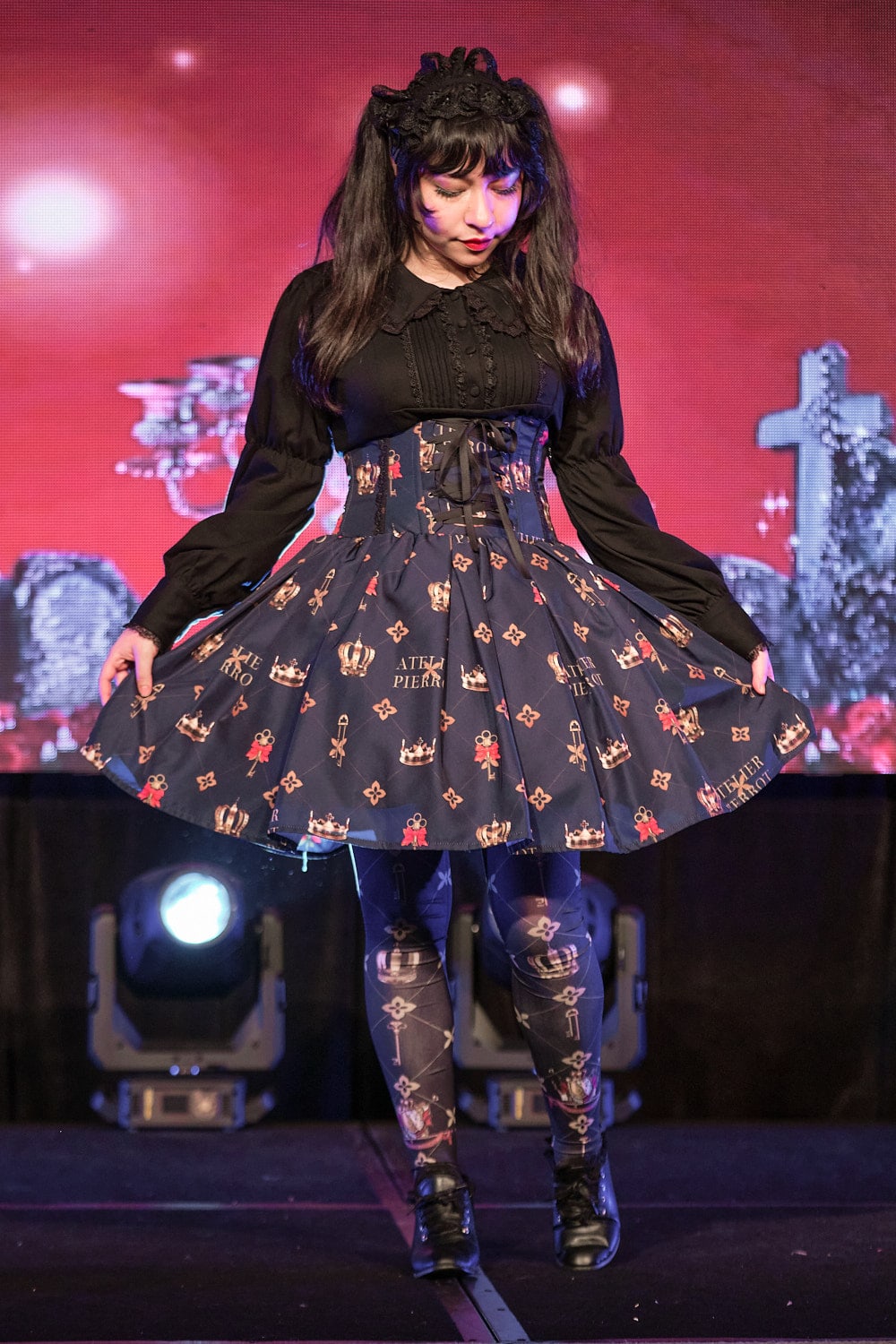 Classic lolita model wearing black cotton cutsew and navy high waist skirt with key print with matching tights - full body, looking down.