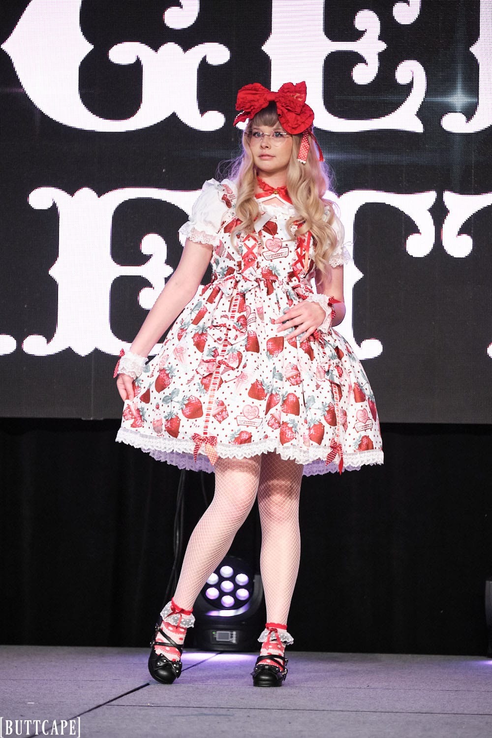 Model 2 wearing white an red strawberry sweet lolita dress, fishnet tights and black shoes - full body 1.