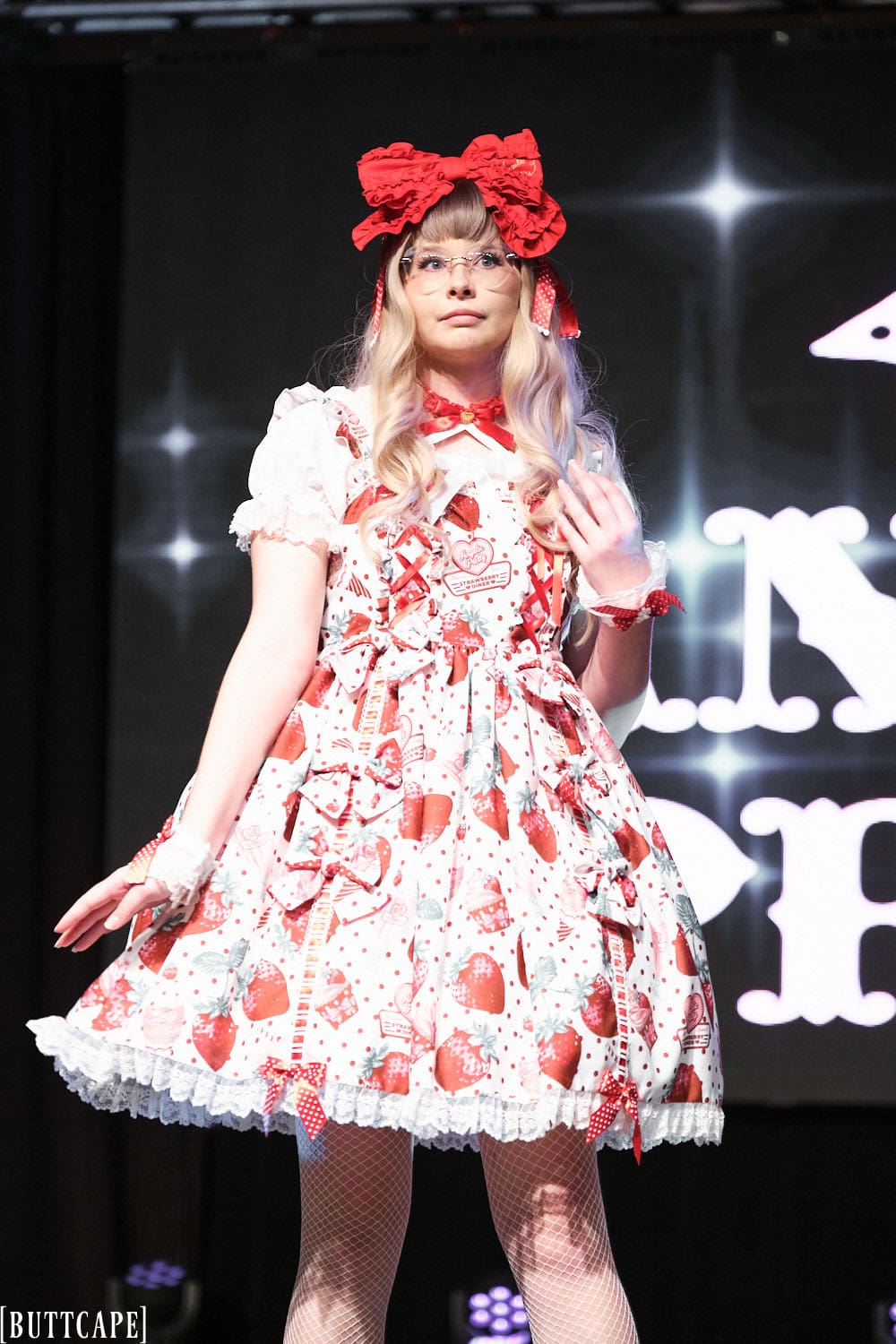 Model 2 wearing white an red strawberry sweet lolita dress, fishnet tights and black shoes - half body 2.