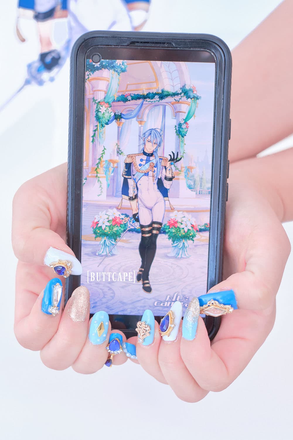 Blue, light blue, white, and gold nail set inspired by Edmond from Nu:Carnival. Two hands hold a phone with Edmond on the screen.