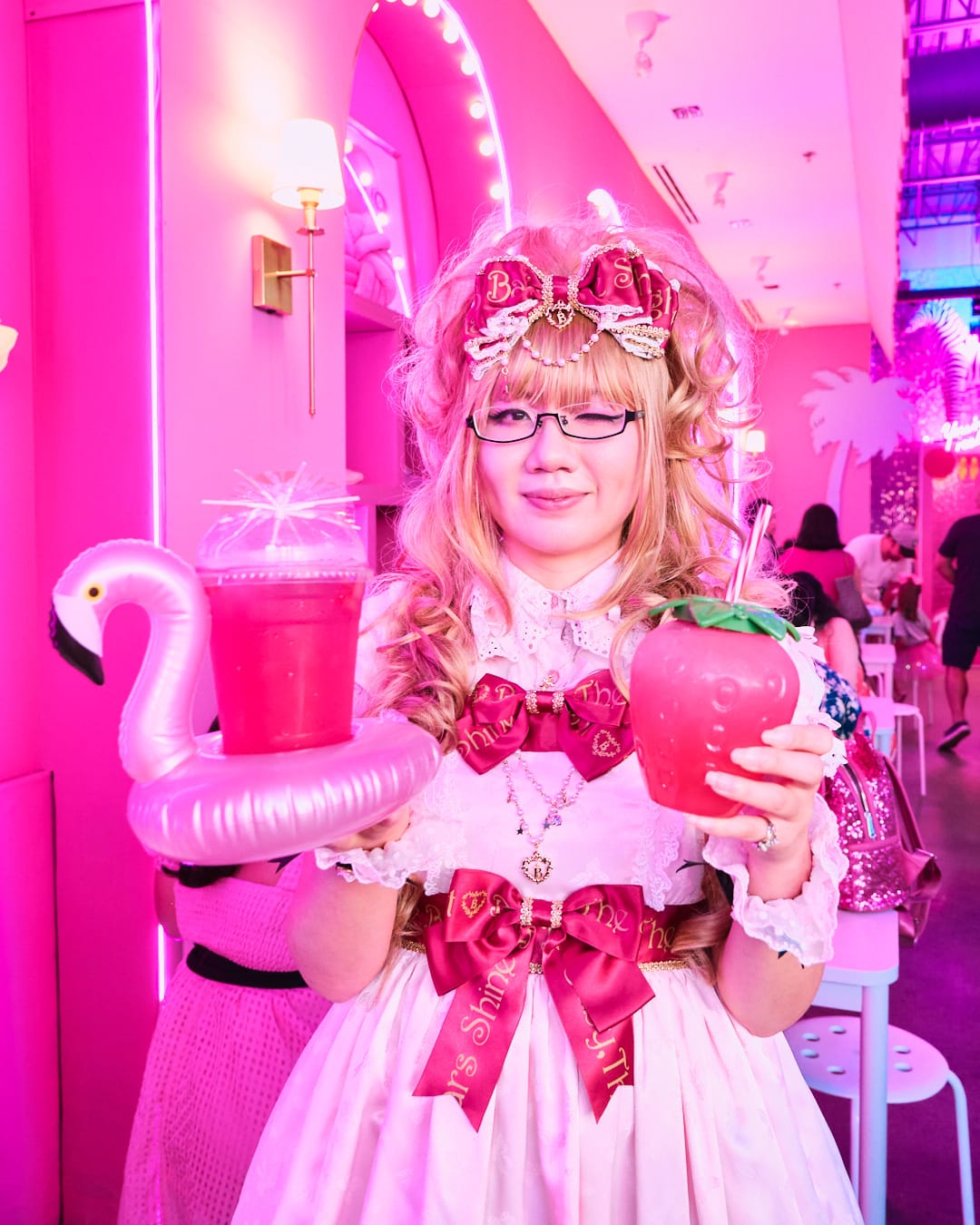 Blogger wearing pink and red lolita dress holding two themed drinks.