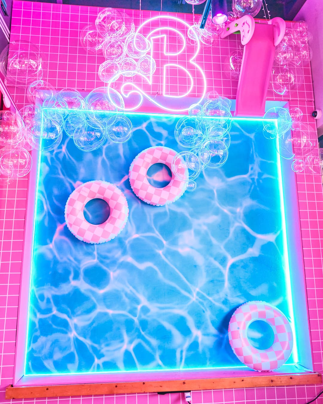 Barbie-inspired poolside photo-op wall. Wall has pink tile and fake pool decor.