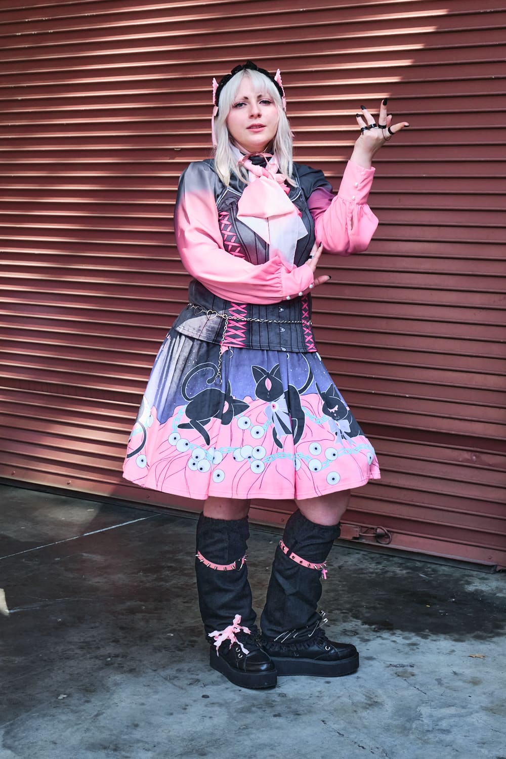 Gothic model wearing pink and black faux corset top with cat print skirt - full body pose 3.
