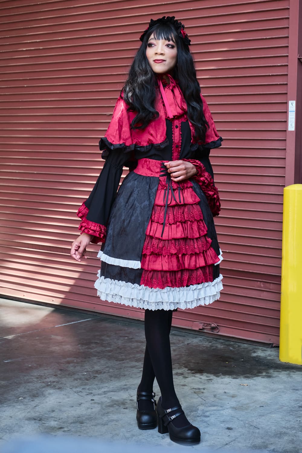 Atelier Pierrot gothic lolita model wearing black, red, and white collaboration set of a capelet, blouse, and skirt set - full body standing pose 4.