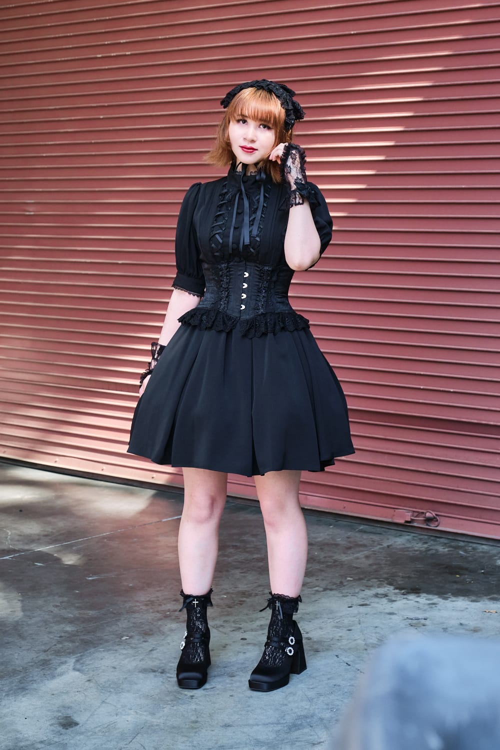 Atelier Pierrot gothic lolita model wearing all black short sleeved dress with black corset - full body standing pose 5.