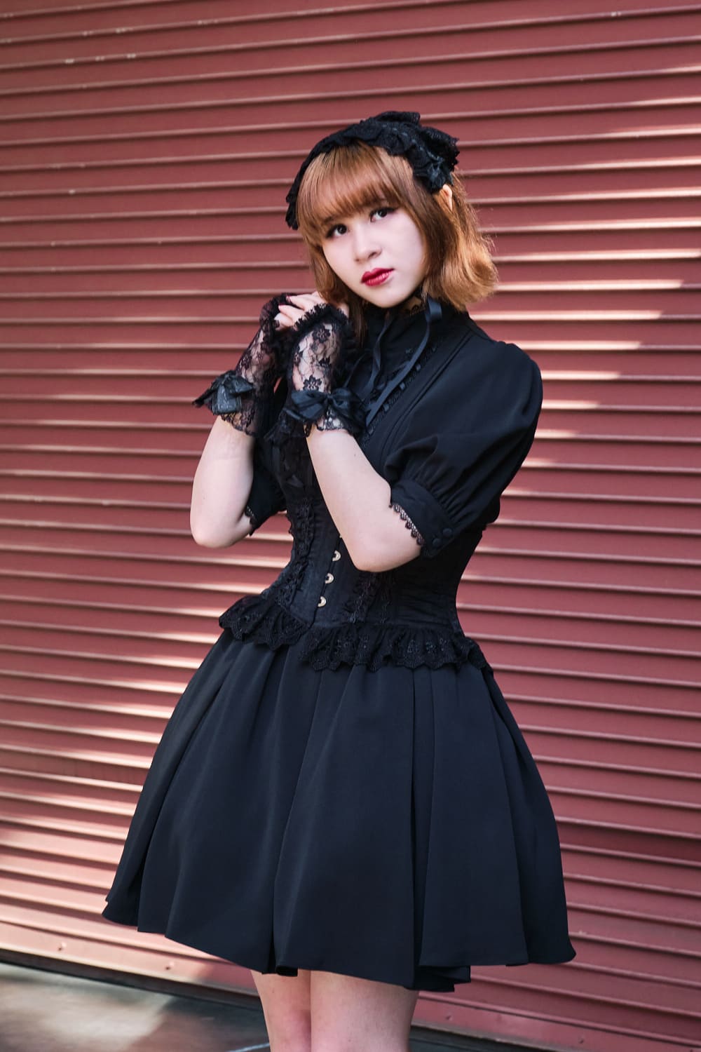 Atelier Pierrot gothic lolita model wearing all black short sleeved dress with black corset - portrait.