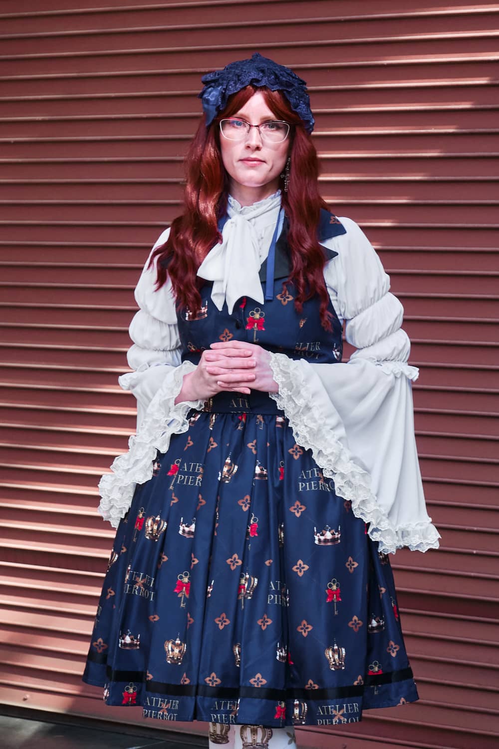 Atelier Pierrot classic lolita model wearing white princess sleeve blouse with crown print vest-style jumperskirt and matching crown tights - portrait.