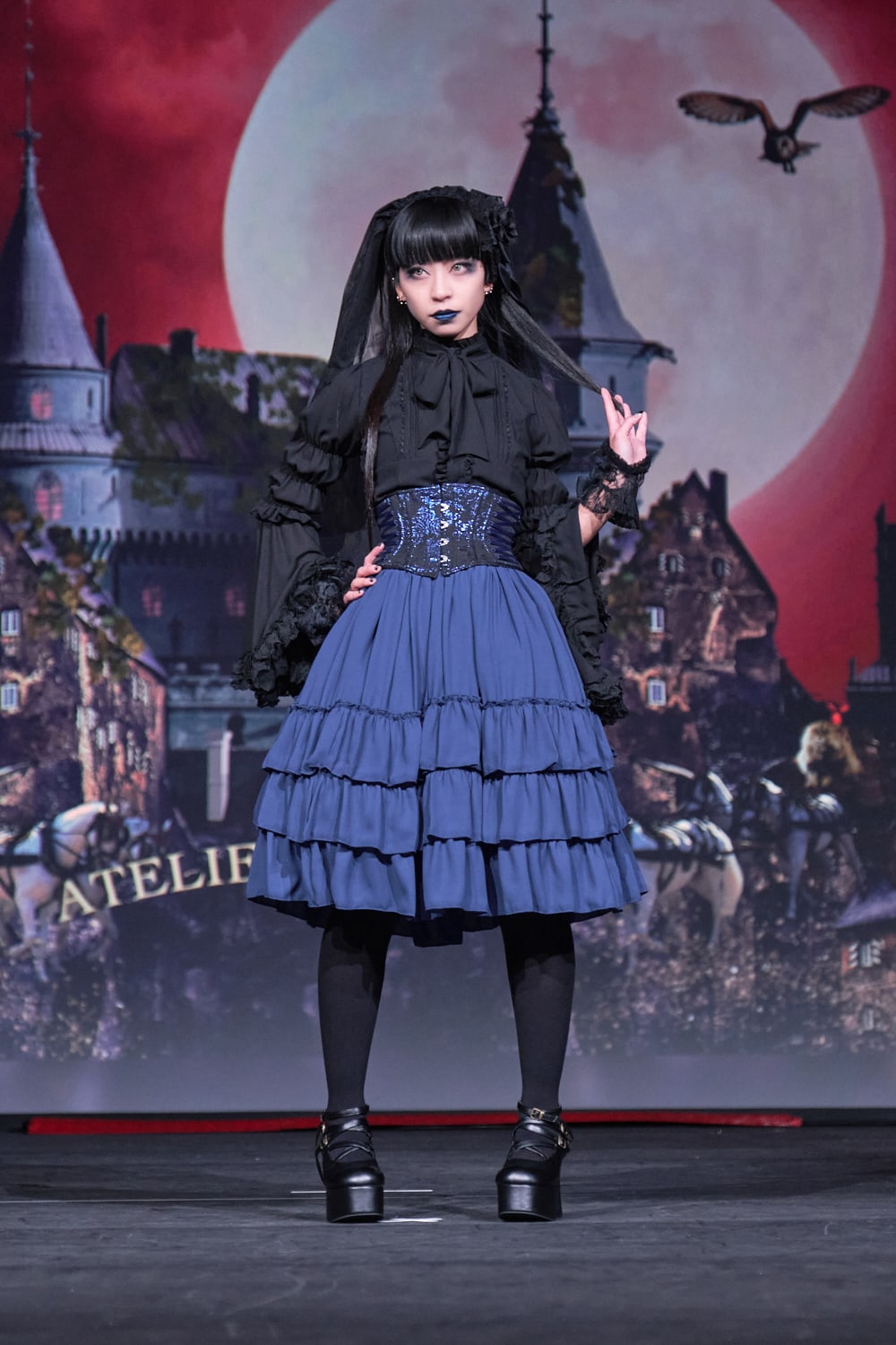 Atelier Pierrot gothic lolita model wearing black blouse, blue corset and skirt - full body standing pose 1.