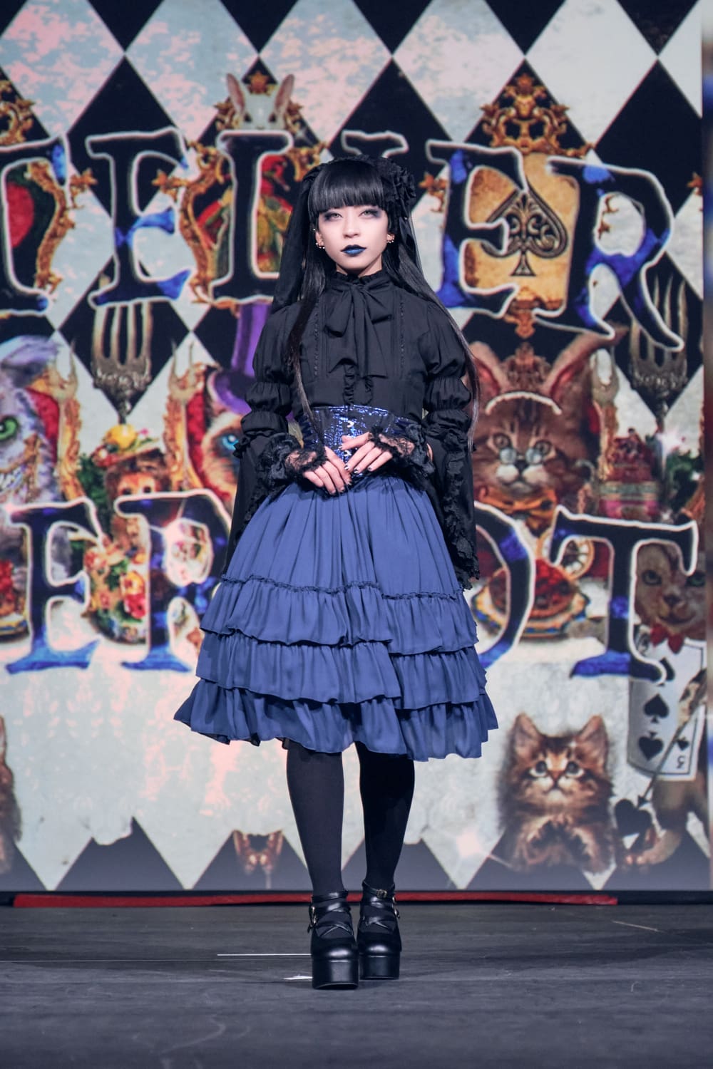 Atelier Pierrot gothic lolita model wearing black blouse, blue corset and skirt - full body walking pose 1.