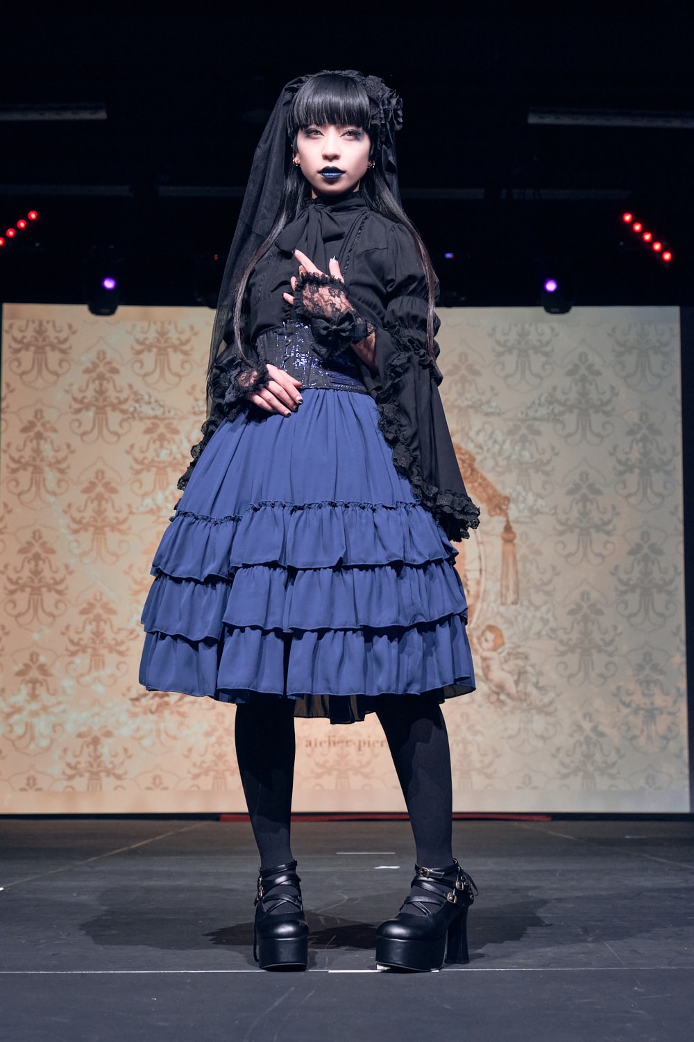 Atelier Pierrot gothic lolita model wearing black blouse, blue corset and skirt - full body standing pose 3.