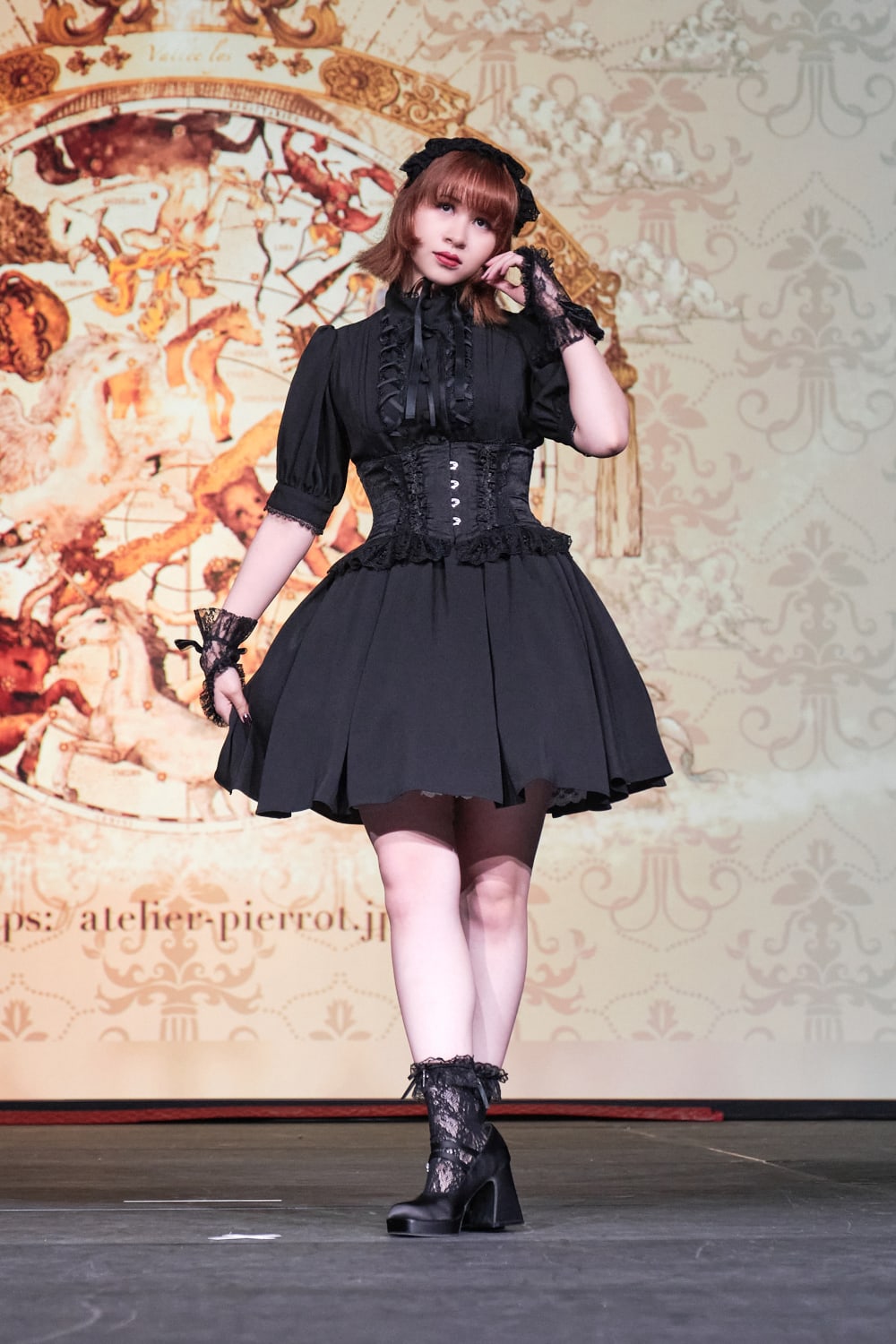 Atelier Pierrot gothic lolita model wearing all black short sleeved dress with black corset - full body standing pose 2.