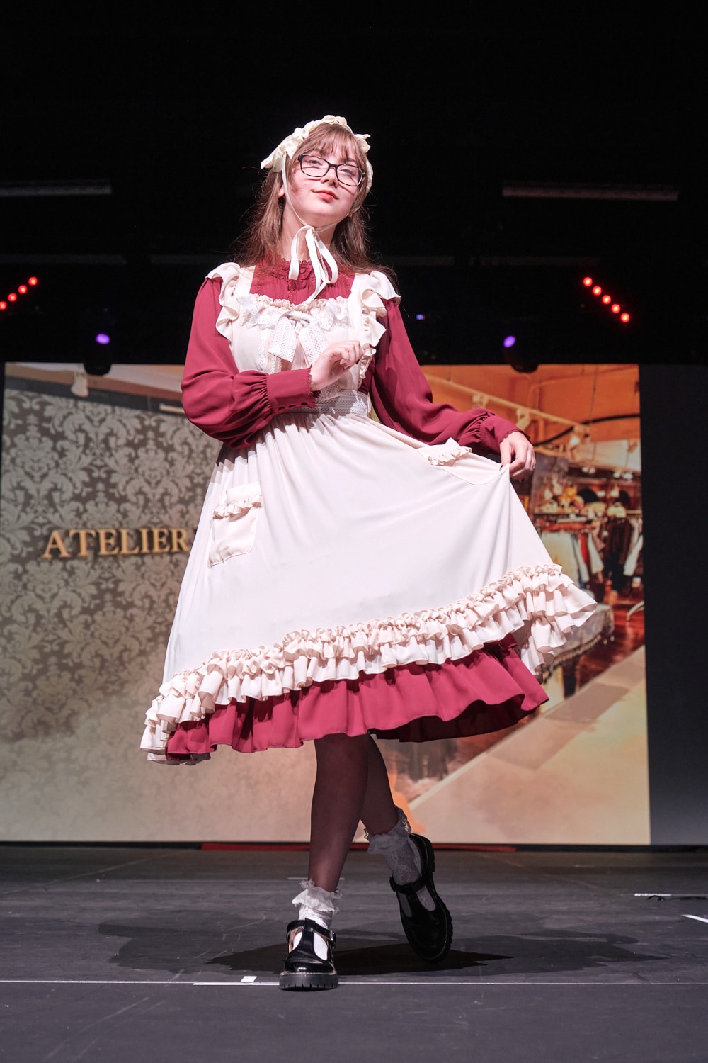 Atelier Pierrot classic lolita model wearing wine red long sleeve one piece dress with ivory apron on top - full body standing pose 2.