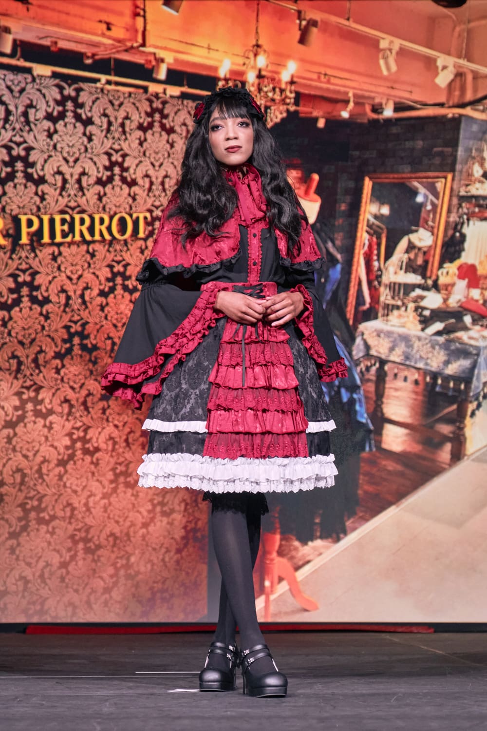 Atelier Pierrot gothic lolita model wearing black, red, and white collaboration set of a capelet, blouse, and skirt set - full body standing pose 1.