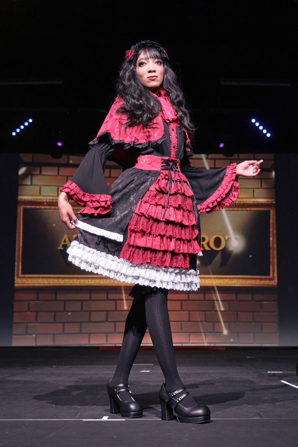 Atelier Pierrot gothic lolita model wearing black, red, and white collaboration set of a capelet, blouse, and skirt set - full body standing pose 2.