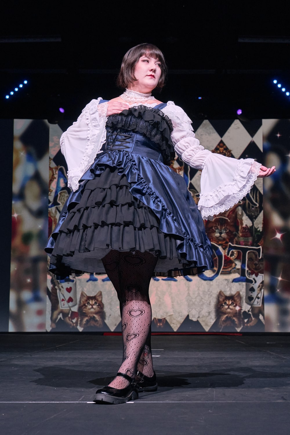 Atelier Pierrot plus size gothic lolita model wearing navy and black bustle corset jumperskirt with white princess sleeve blouse - full body standing pose 2.