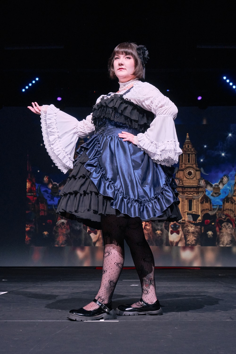 Atelier Pierrot plus size gothic lolita model wearing navy and black bustle corset jumperskirt with white princess sleeve blouse - full body standing pose 3.
