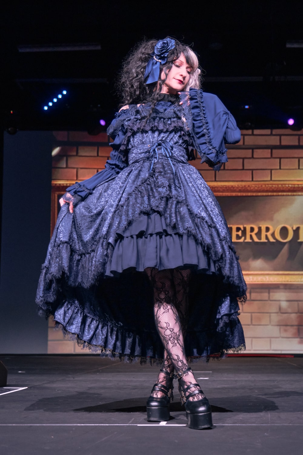 Atelier Pierrot gothic lolita model wearing all navy lace high low fishtail jumperskirt and navy princess sleeve blouse - full body standing pose 4.