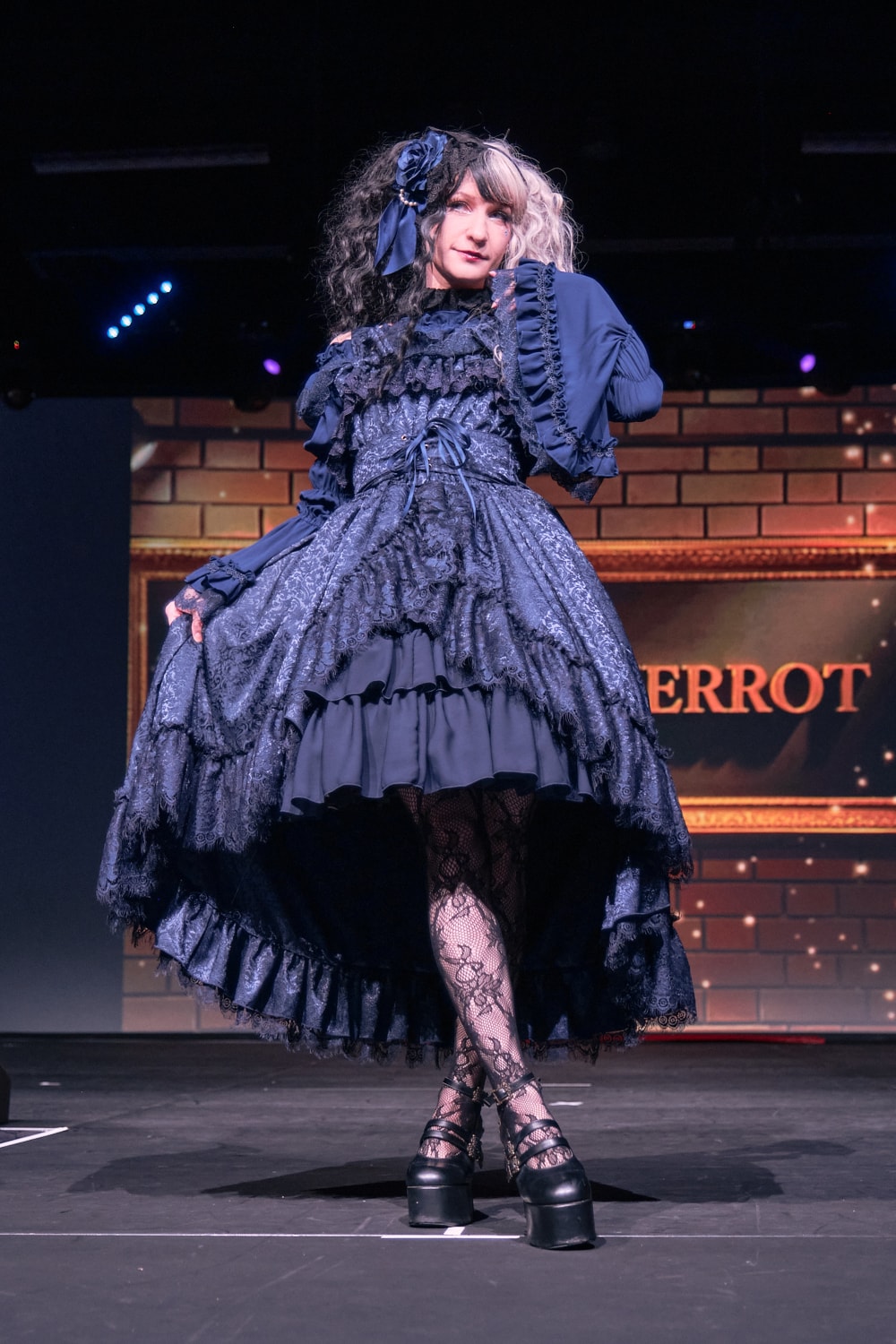 Atelier Pierrot gothic lolita model wearing all navy lace high low fishtail jumperskirt and navy princess sleeve blouse - full body standing pose 5.