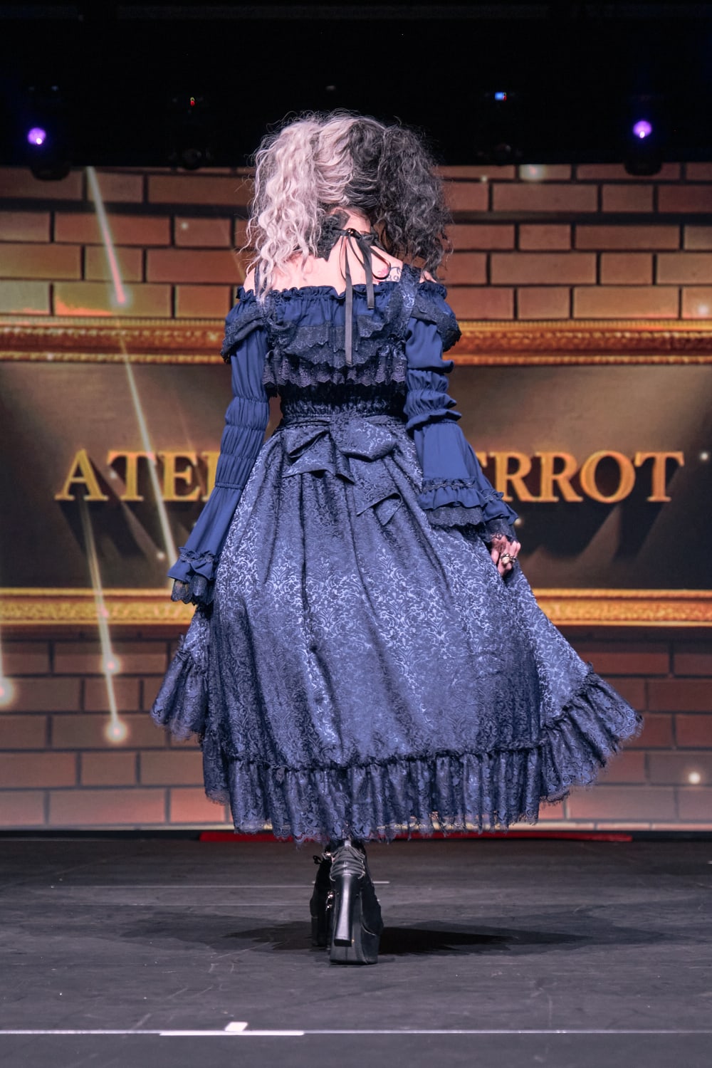 Atelier Pierrot gothic lolita model wearing all navy lace high low fishtail jumperskirt and navy princess sleeve blouse - full body walking back pose 1.