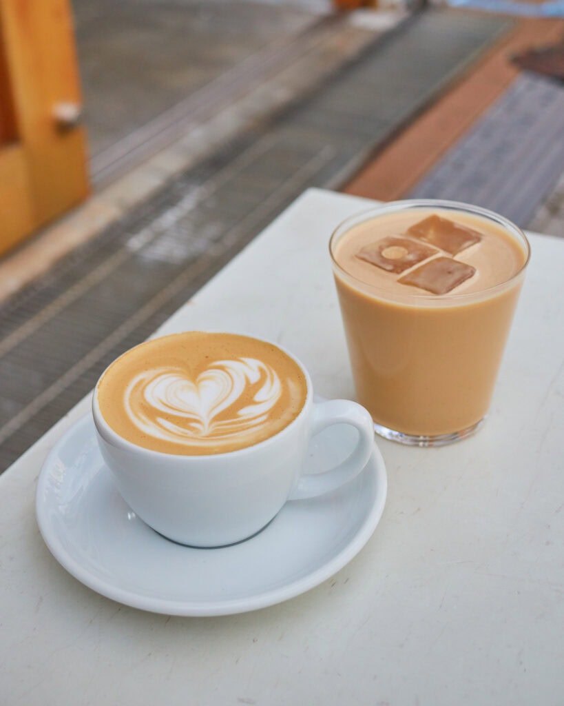 Latte with heart latte art with an iced latte in the back