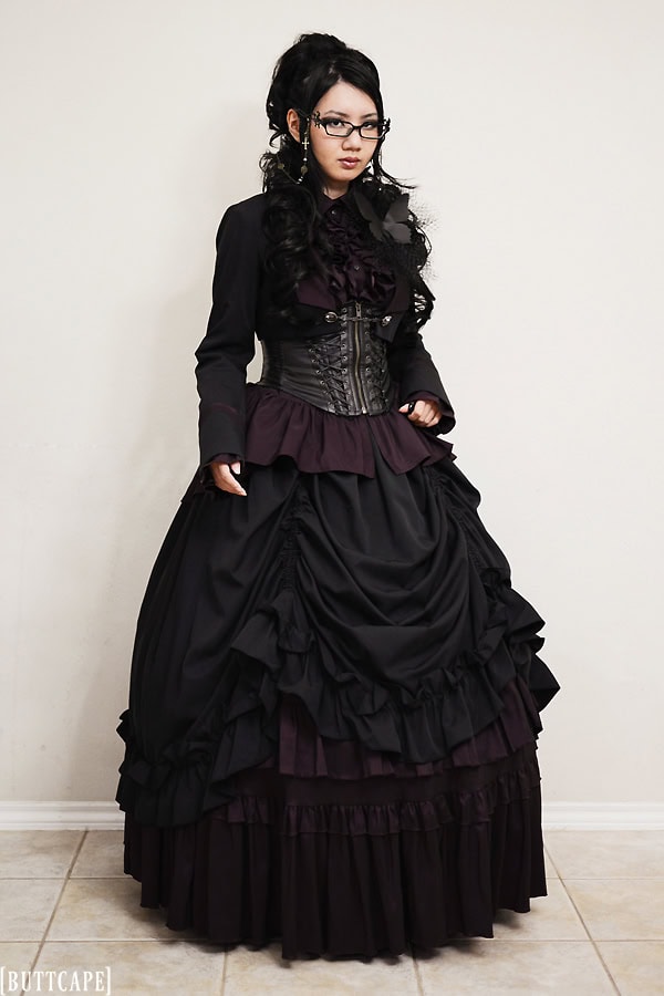 Gothic aristocrat outfit with layered tops and voluminous bustle skirt in black and bordeaux colors.