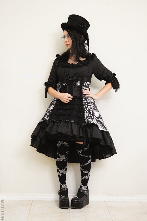 Gothic lolita with top hat, highlow dress, over knee socks, and platform wedge shoes.