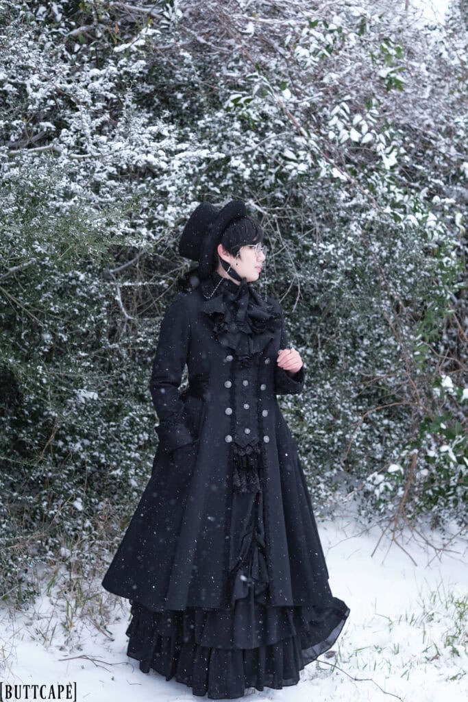 Victorian gothic person standing in snow covered thicket.