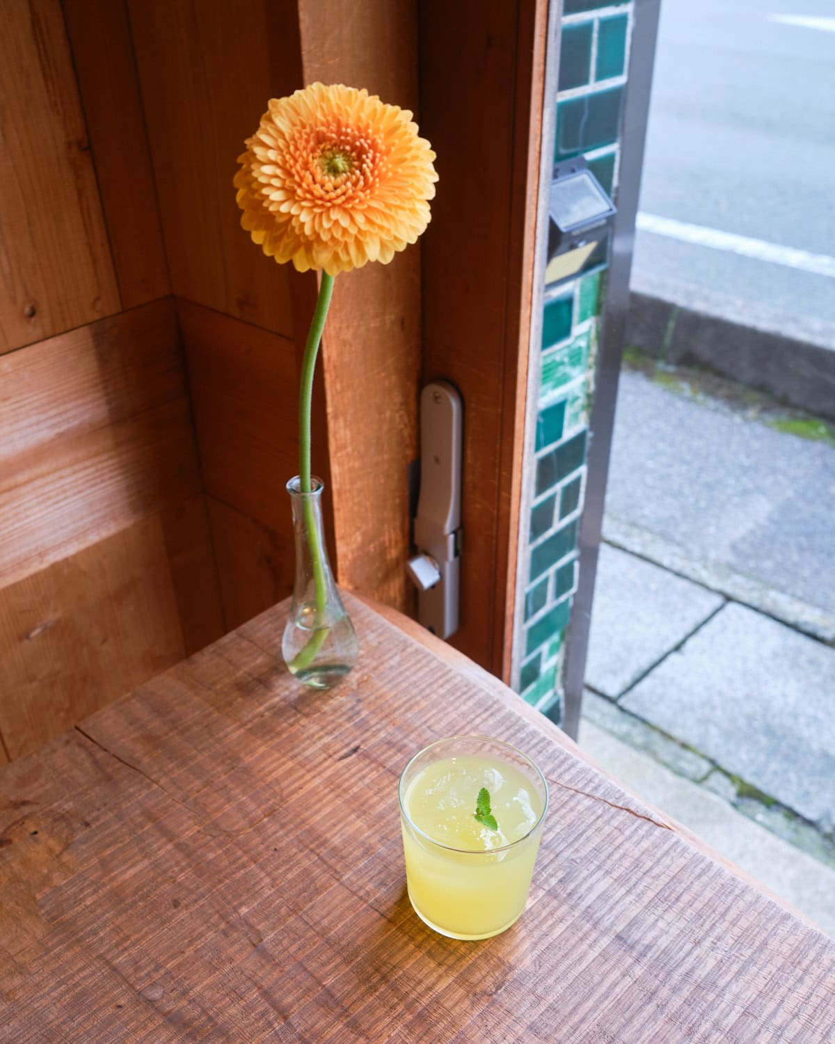 Hagi's specialty natsumikan juice next to a flower at ruco guest house and cafe