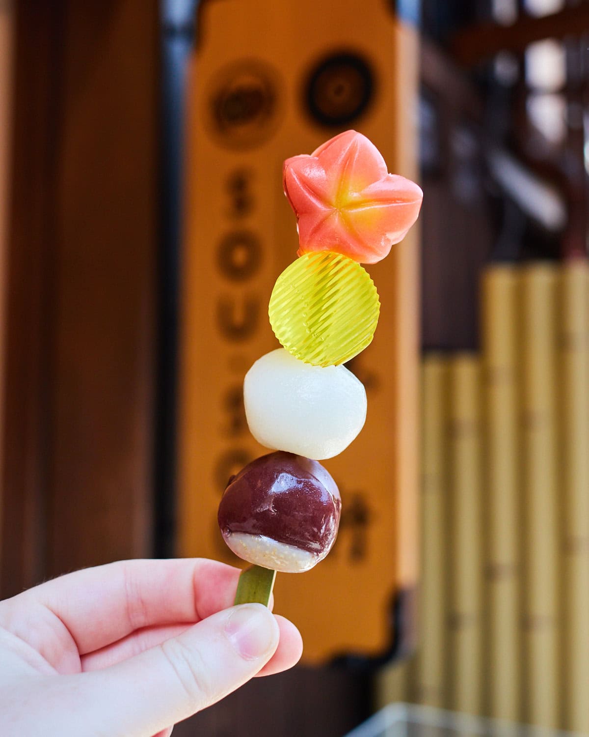 Itoken x sou sou wagashi on a stick in front of shop sign