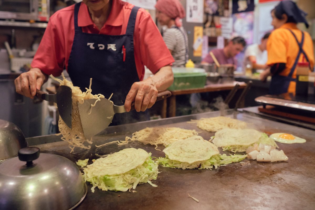 Hiroshima style okonomiyaki noodles being flipped