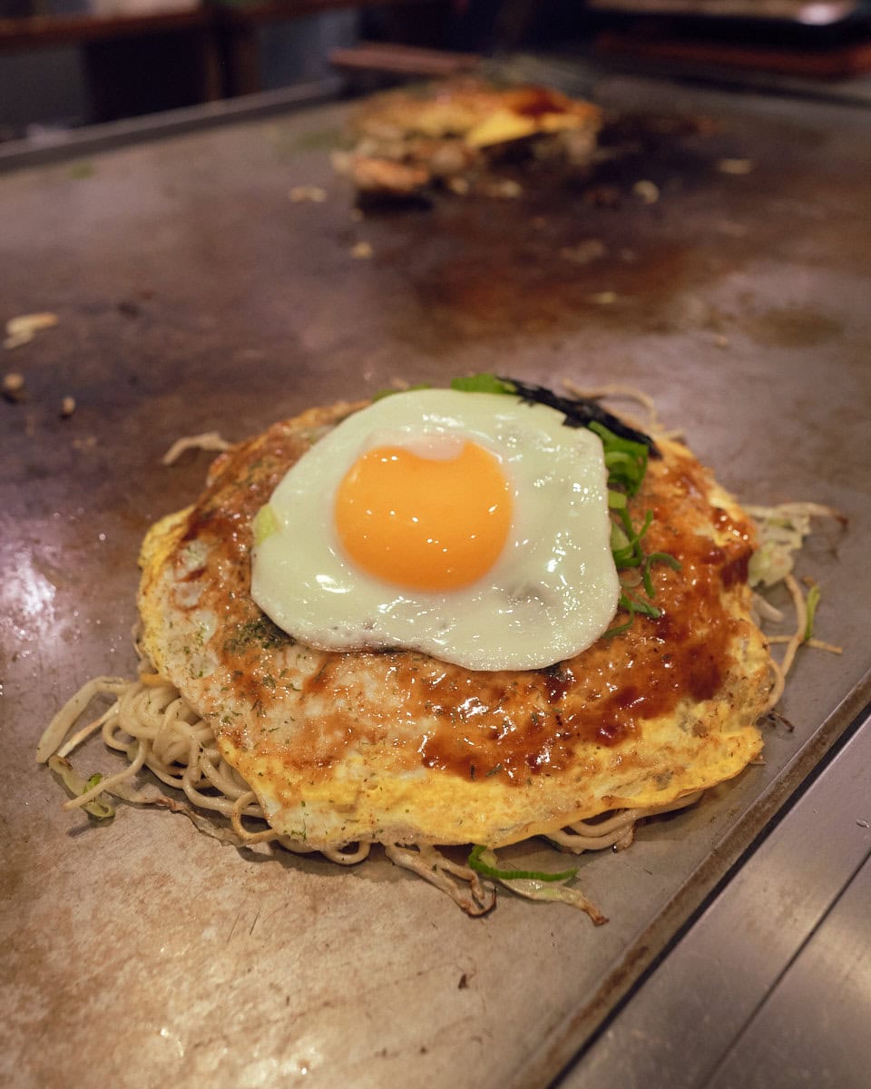 hiroshima style okonomiyaki topped with a fried egg