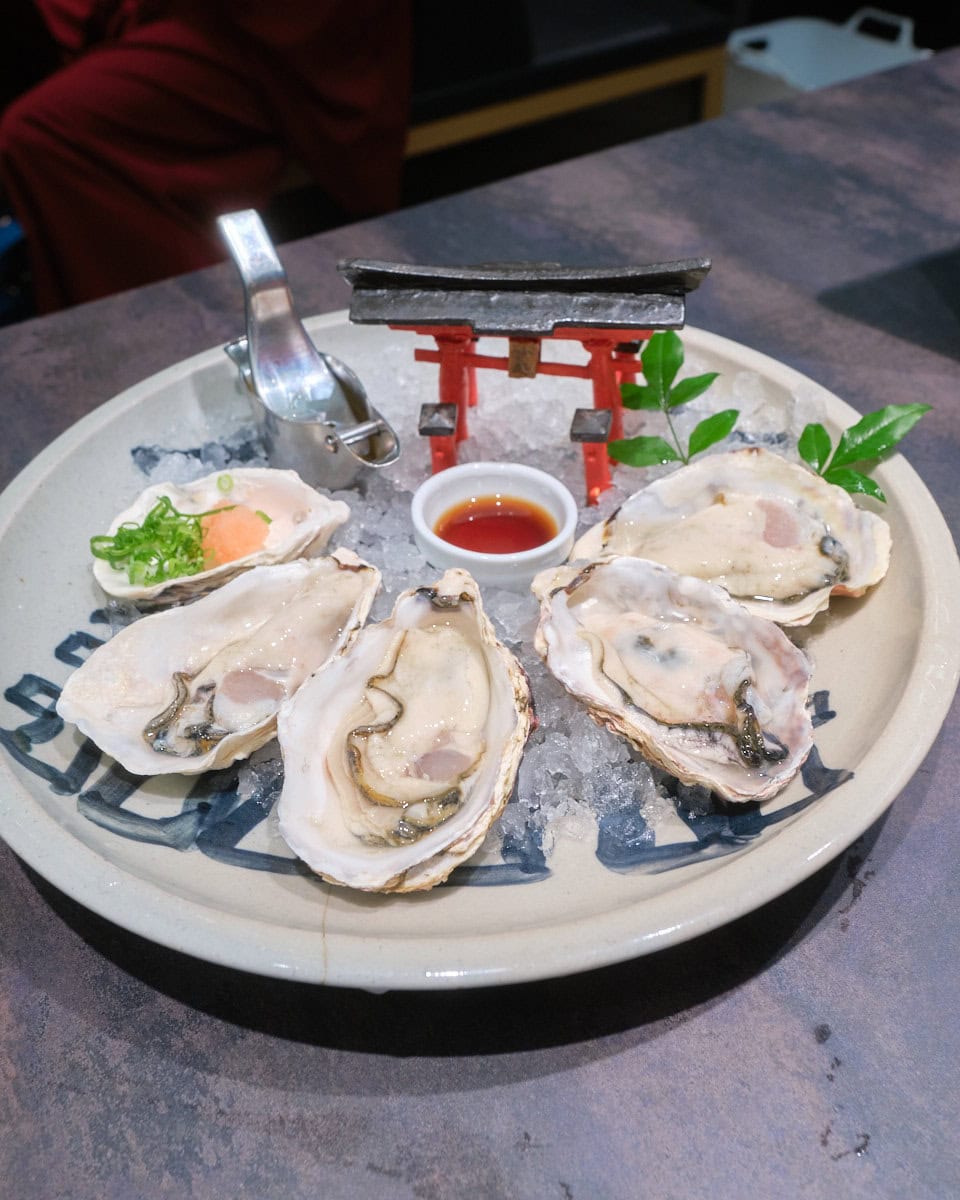 raw hiroshima oysters on ice with a miyajima inspired tori gate on the plate