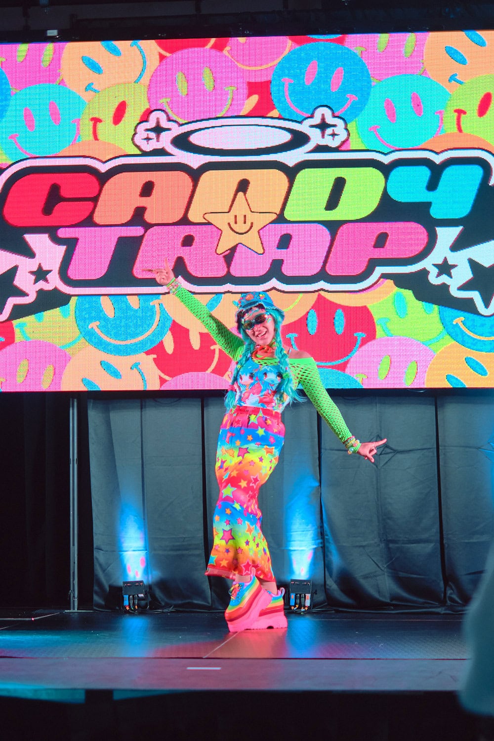 Candy Trap model #2 wears multicolor rainbow anime girl t-shirt over green mesh top and maxi skirt with stars and stripes.