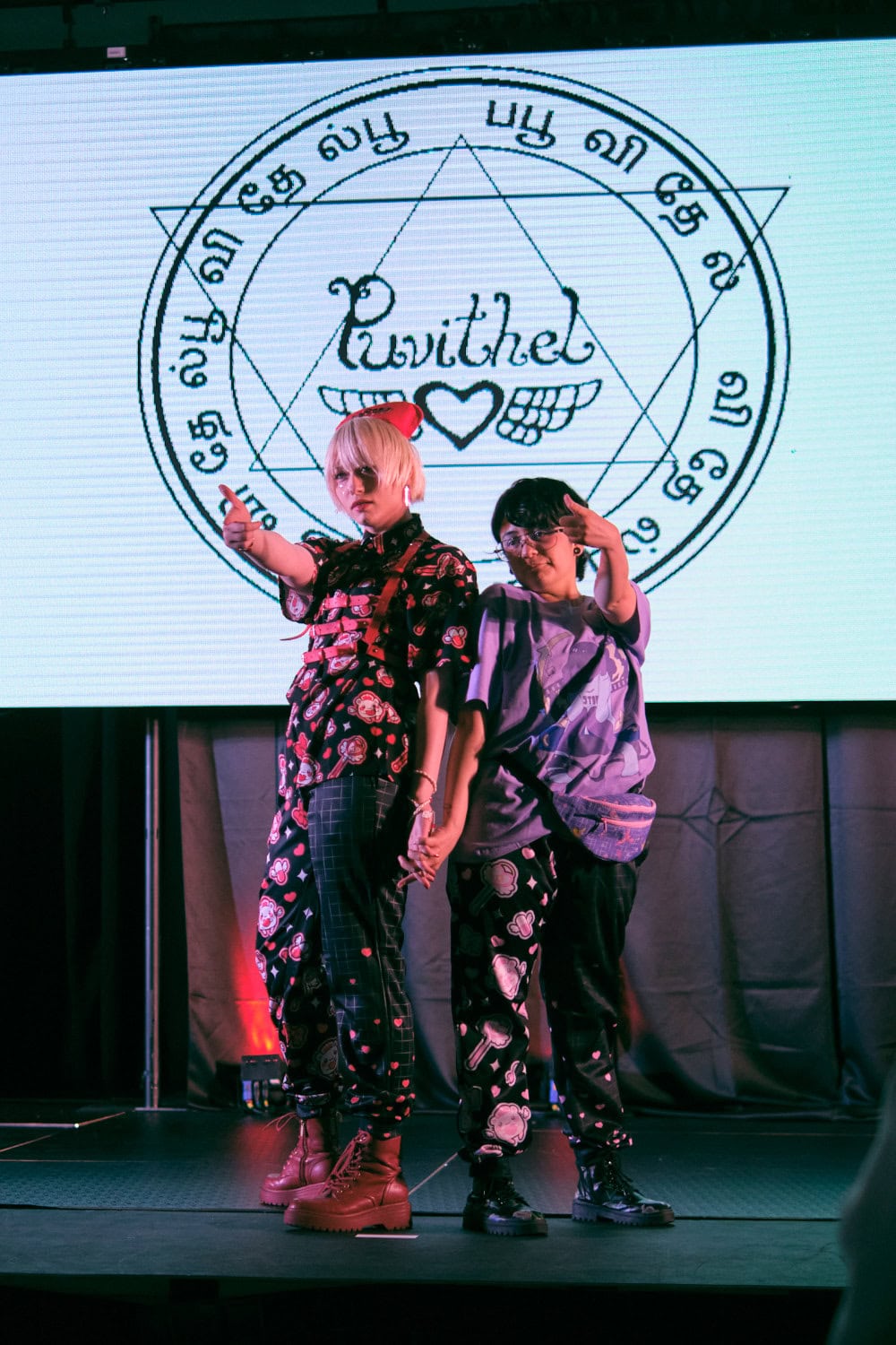 Puvithel models #4 and #5 standing next to each other holding hands and extending arms to look cool.