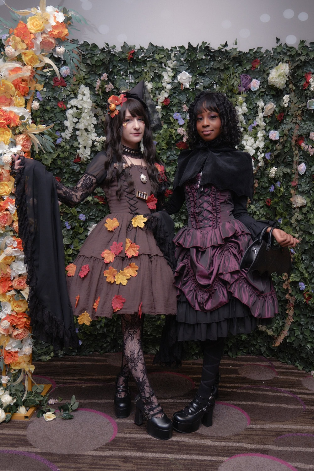 Two gothic lolitas standing next to each other.
