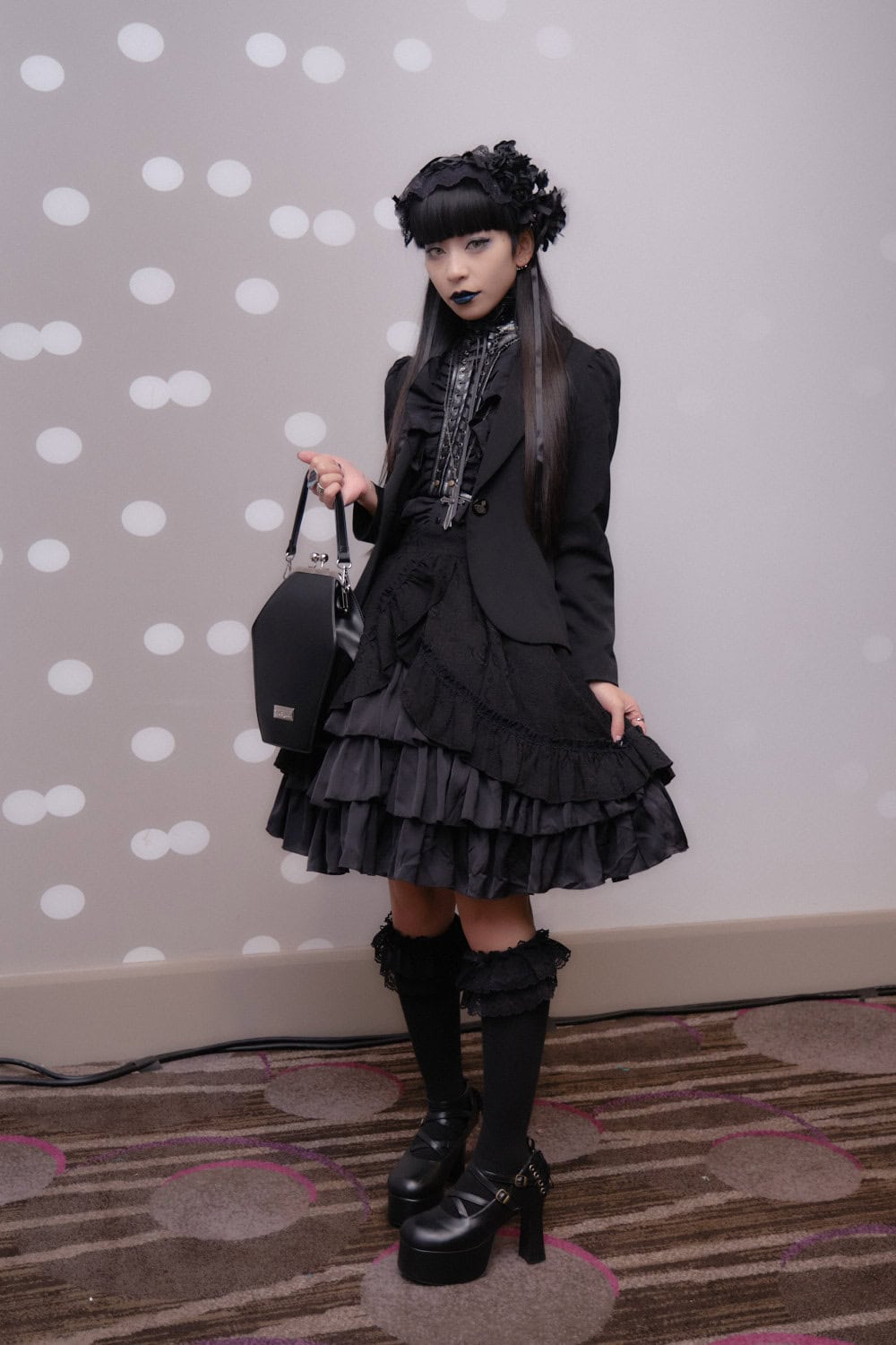 Gothic lolita wearing all black blazer and frill skirt.