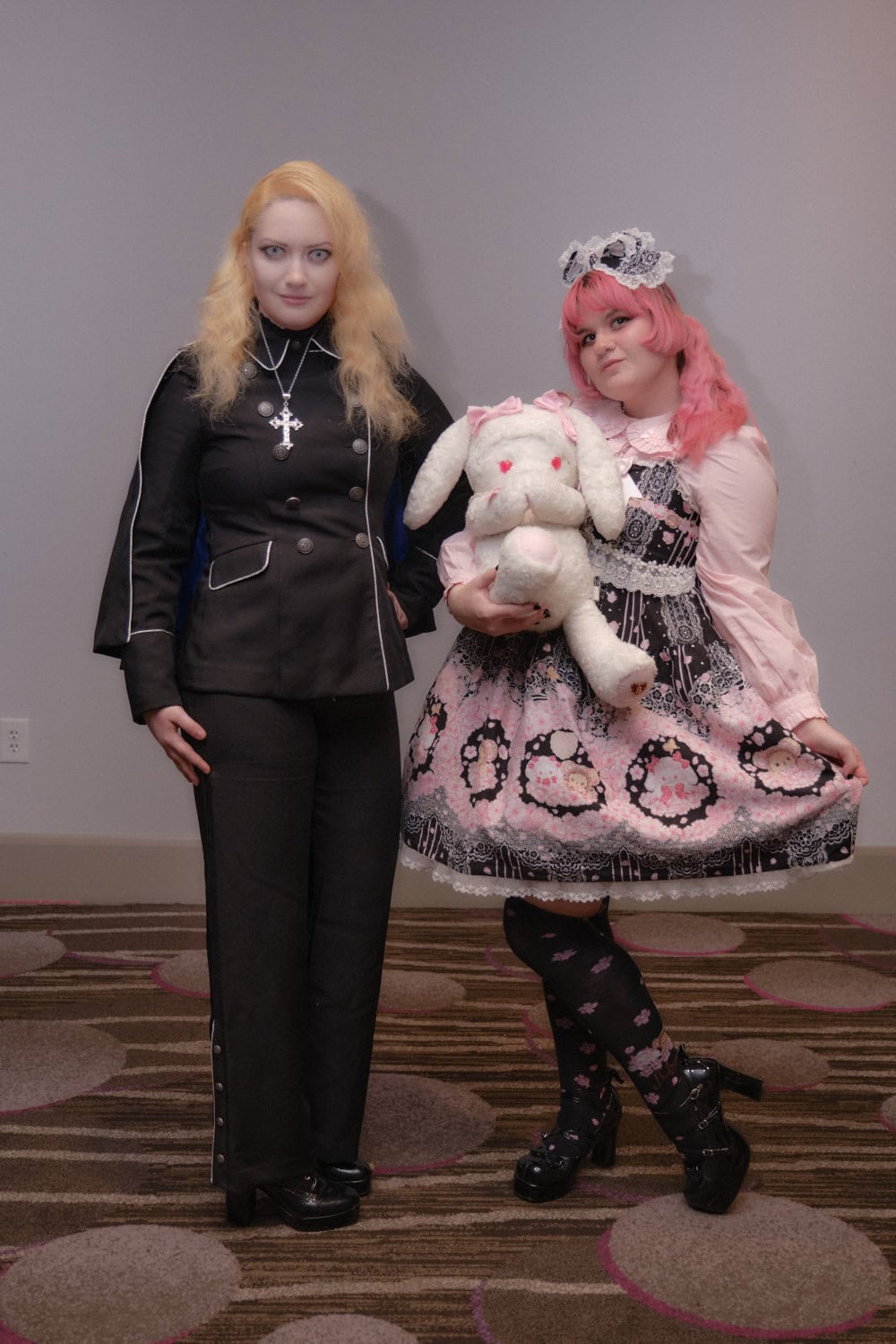 Gothic aristocrat standing on left and sweet lolita wearing black and pink on right.